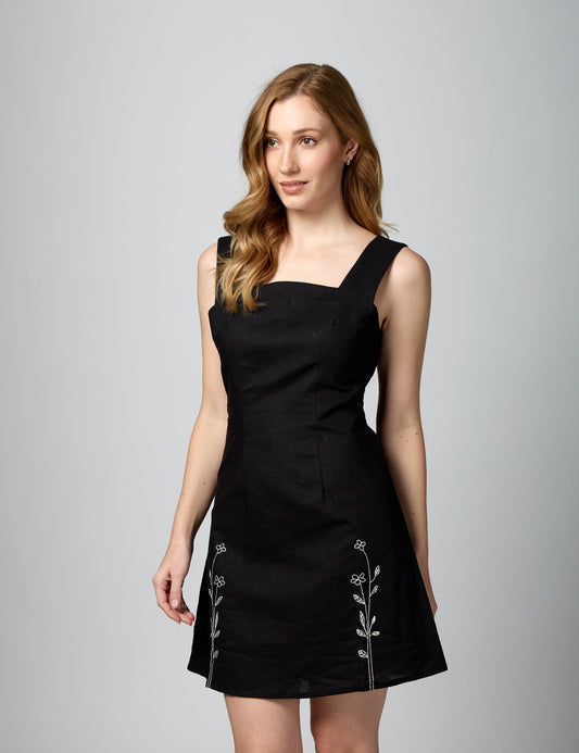 Three-quarter profile of sleeveless black mini dress with square neck and breathable natural lining.