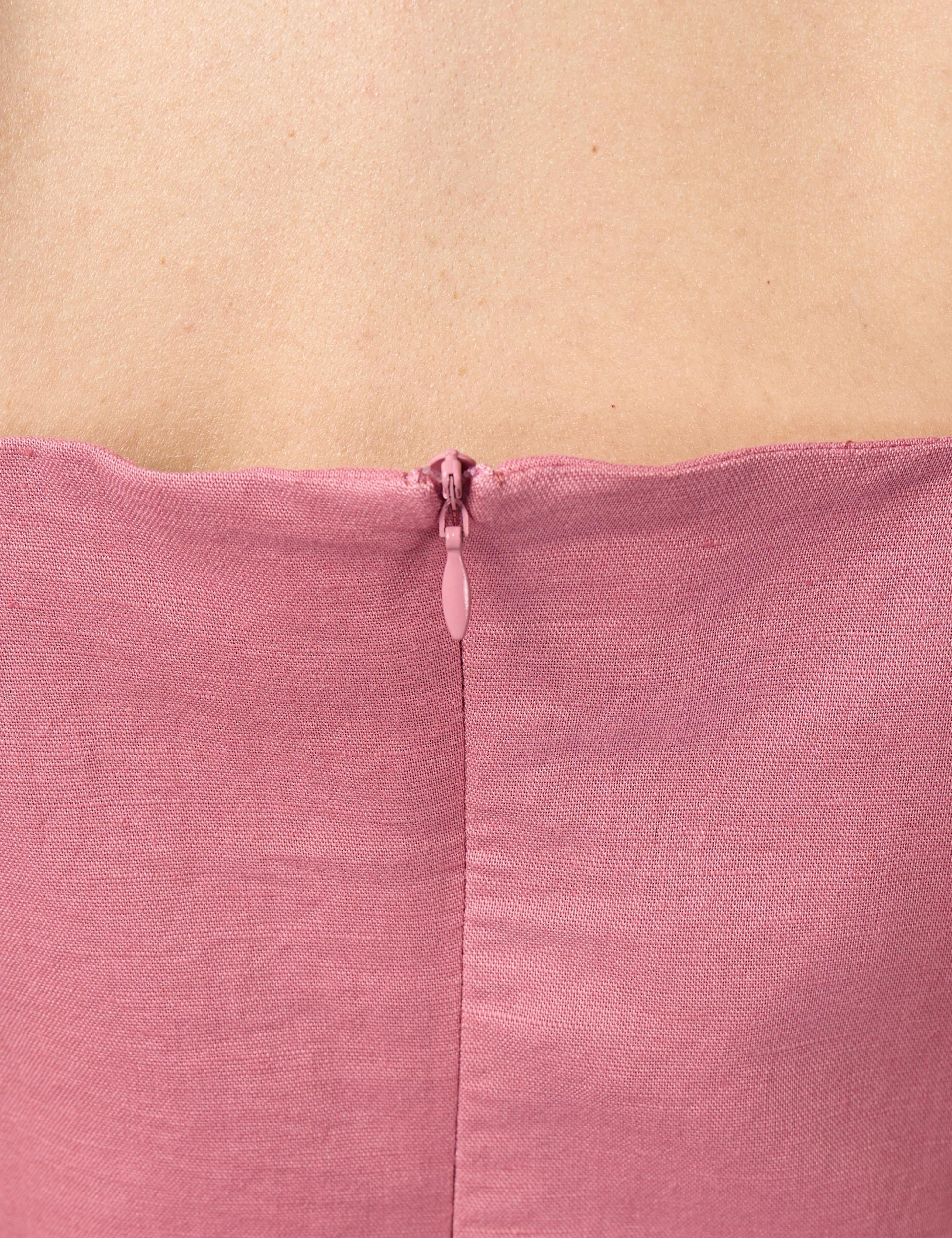 Close-up of high-quality YKK invisible zip enclosure on the back of a pink sustainable luxury dress.