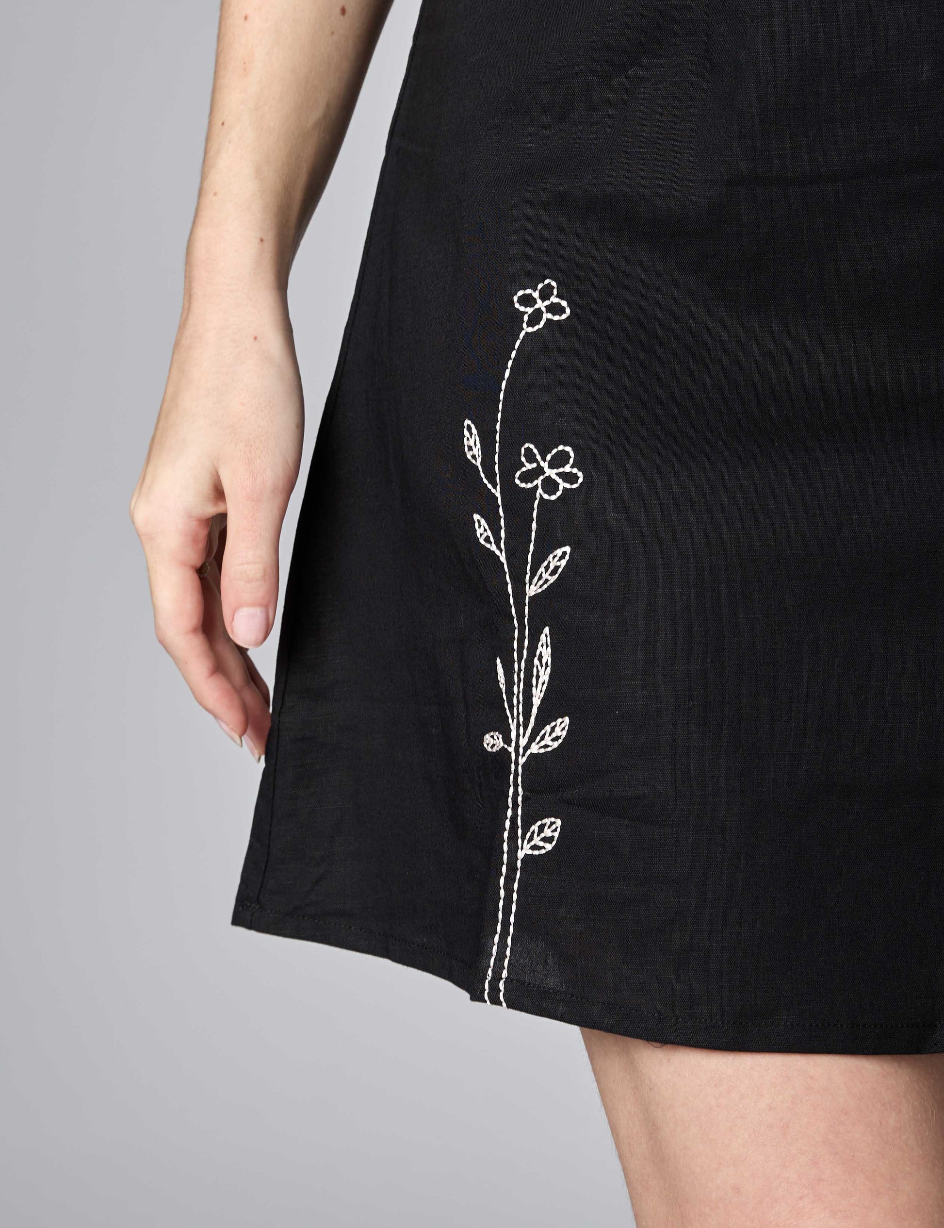 Detailed shot of durable silver thread embroidery on a classic black sustainable summer dress.