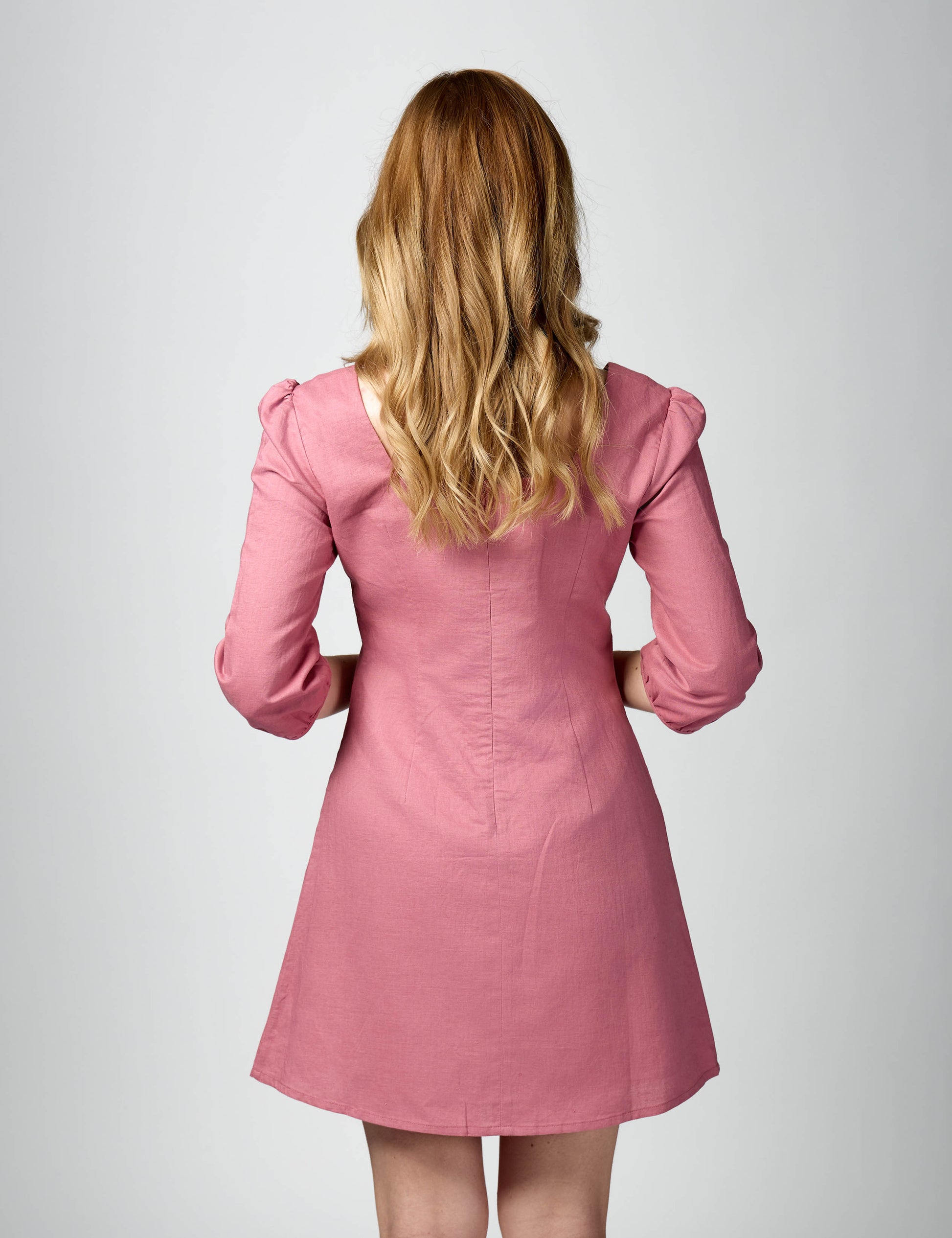 Rear three-quarter profile of pink 3/4 sleeve summer dress highlighting the tailored fit and silhouette.