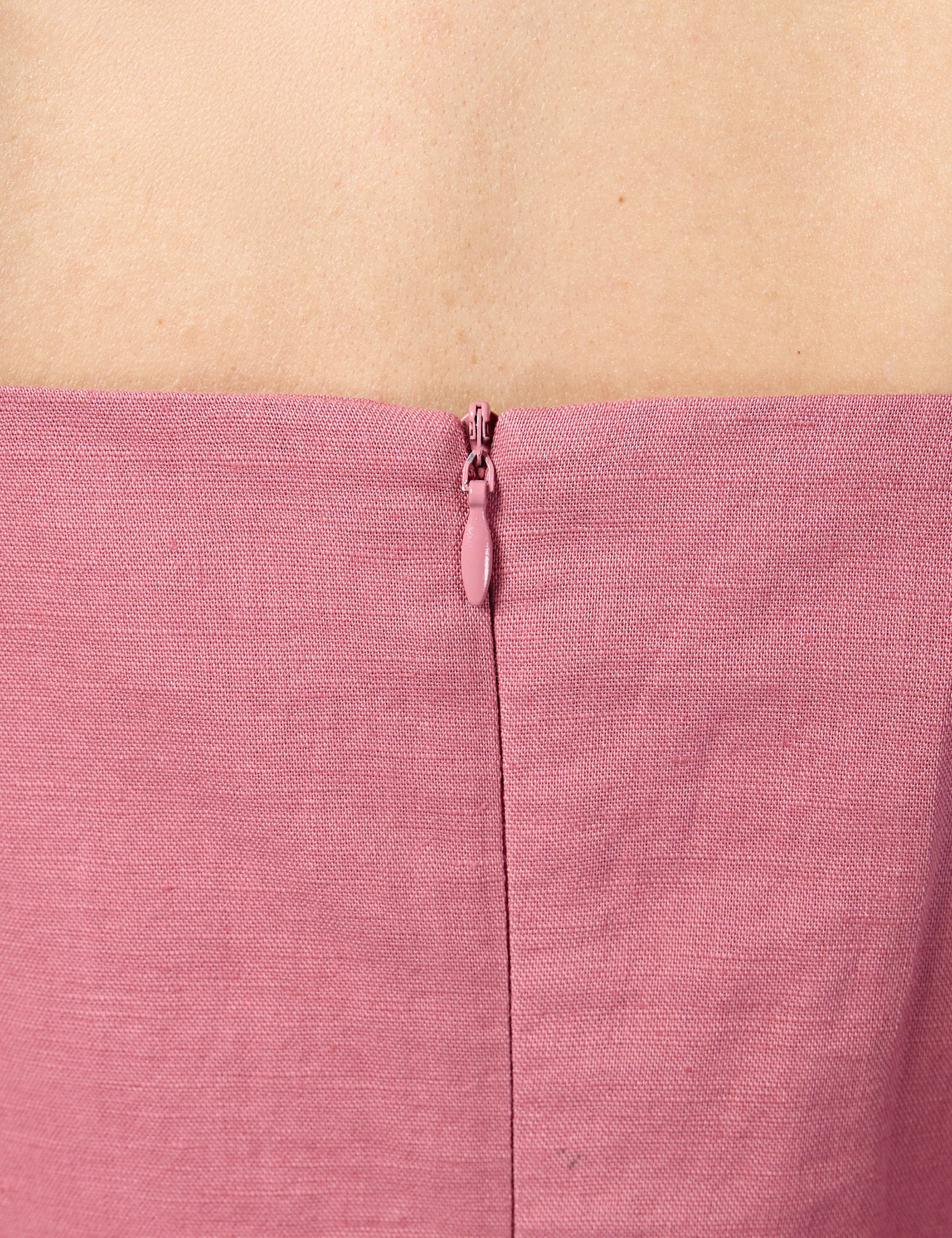 Close-up of high-quality YKK invisible zip enclosure on the back of a pink 3/4 sleeve sustainable dress.